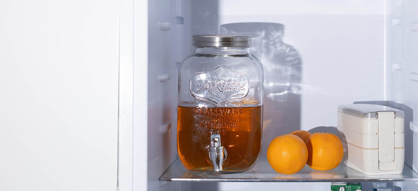 Open refrigerator with cold brew tea and various food items on shelves